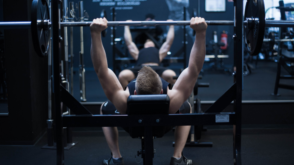 A person is laying on a bench in a gym.