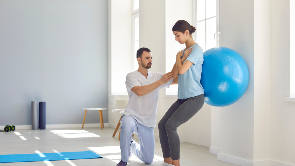 A physiotherapist working with a patient on an exercise ball