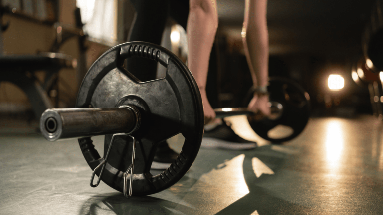 a person is lifting a barbell in a gym