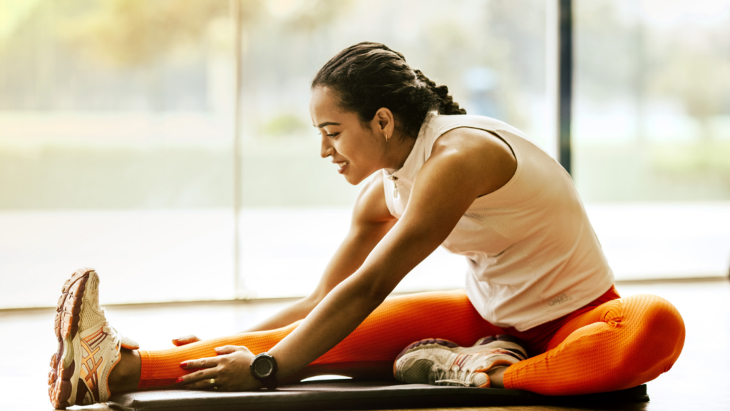 a person stretches their legs while sitting on a mat