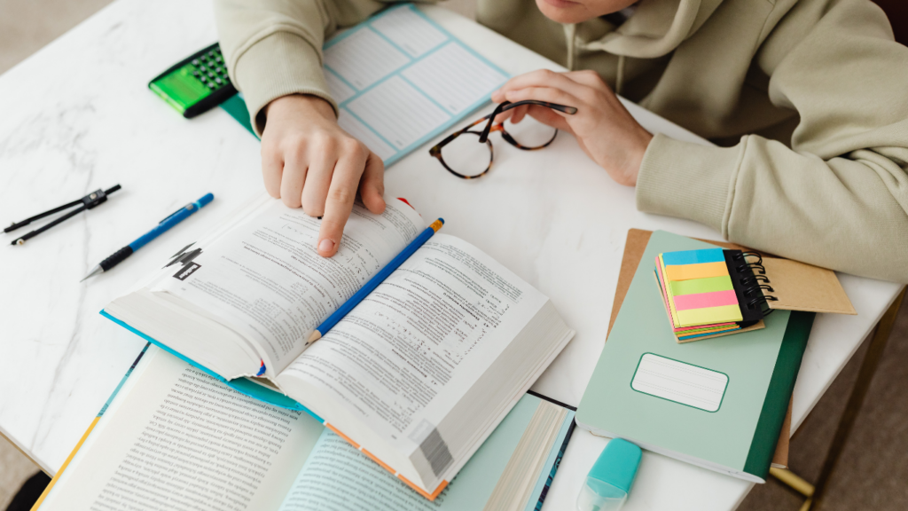 a person sitting at a table with books and pens