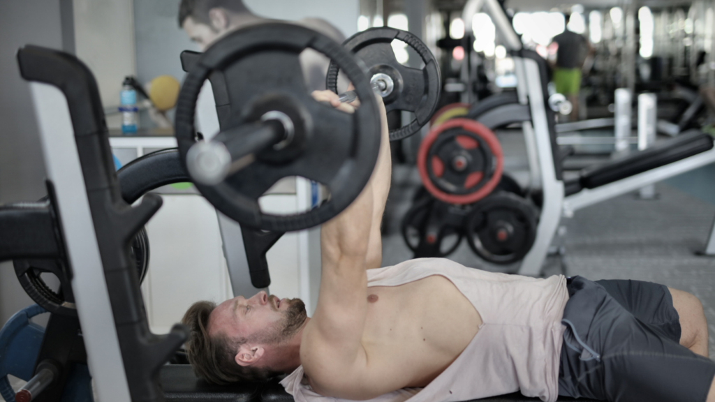 A person is laying on a bench in a gym.