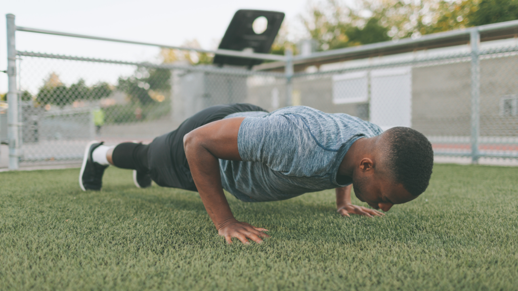 a person is doing push ups on a grass field