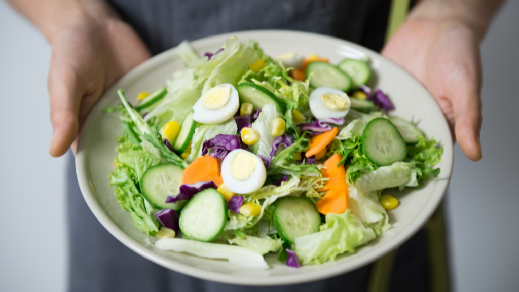 a person holding a plate with a salad on it