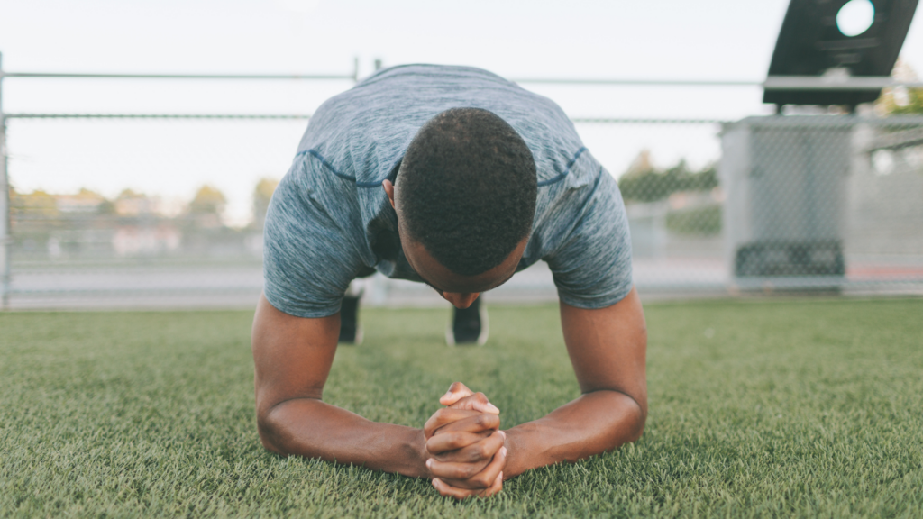 a person is doing push ups on a grass field