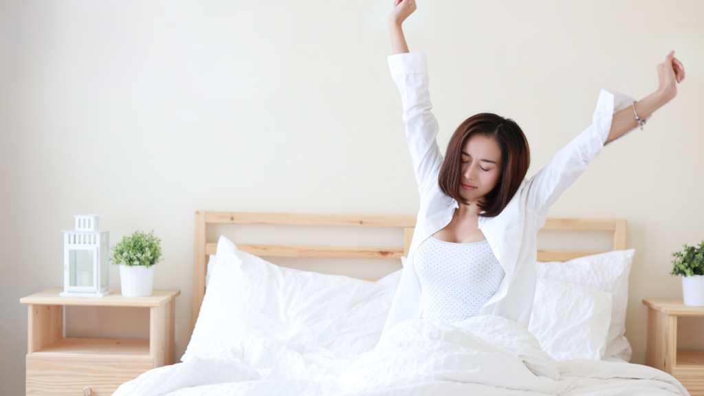 a person is laying on a bed with their arms up in the air