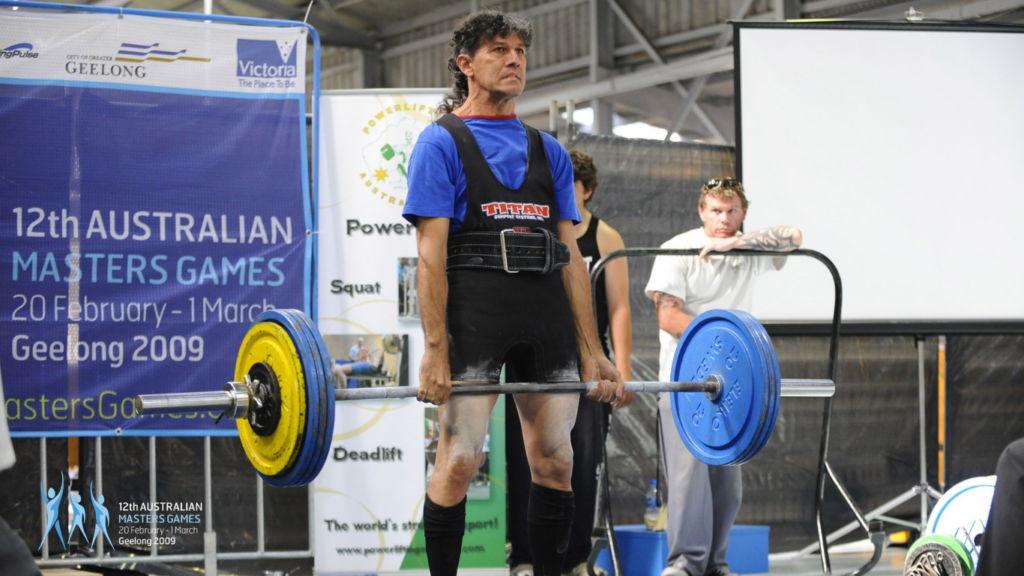 a person is lifting a barbell in a gym