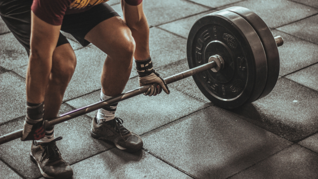 a person is squatting with a barbell in a gym