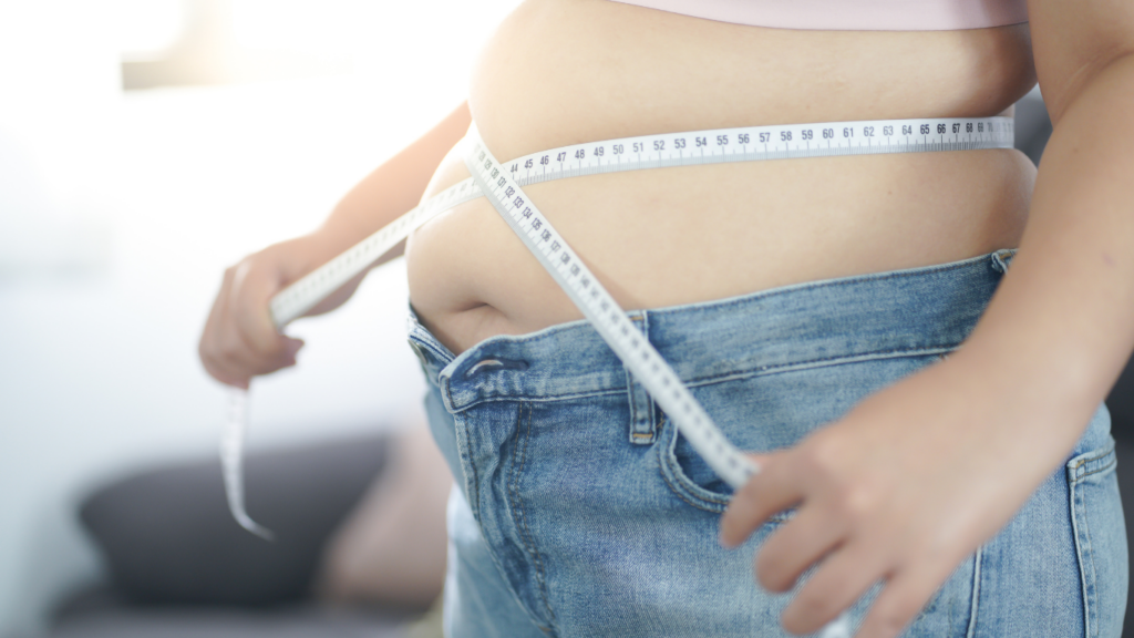 a person measuring their waist with a tape measure