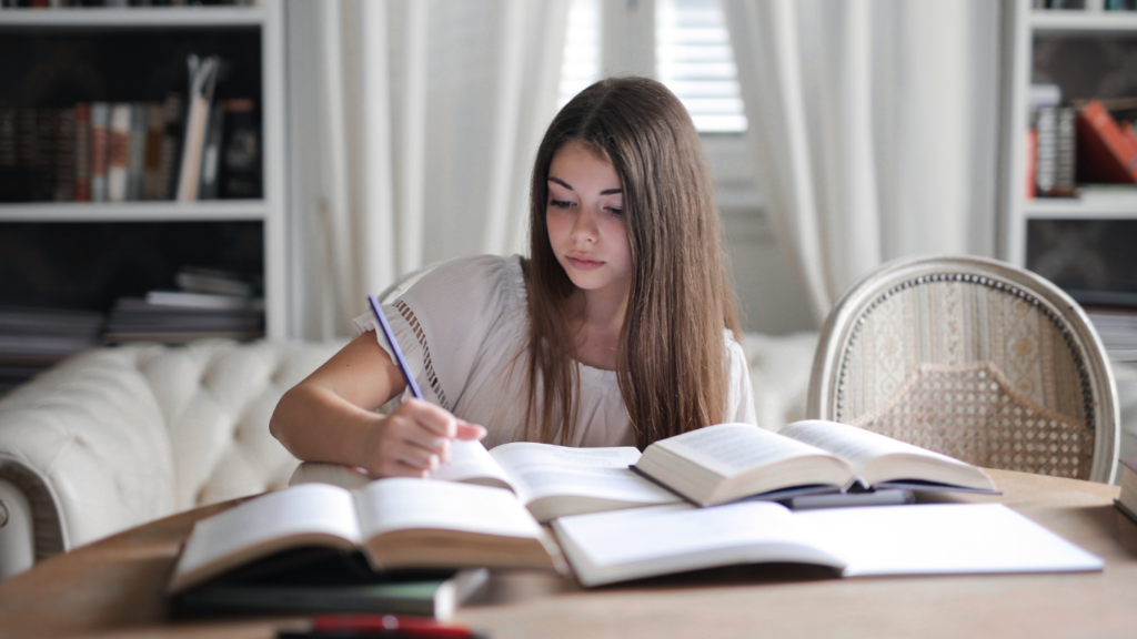 a person sitting at a table with books and pens