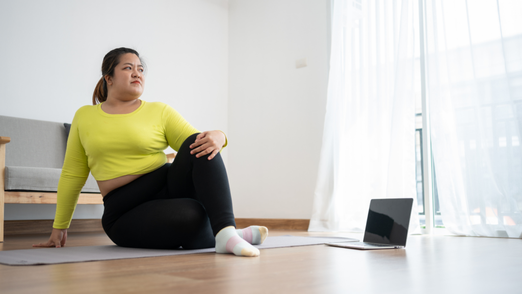 a person sitting on a yoga mat in front of a laptop